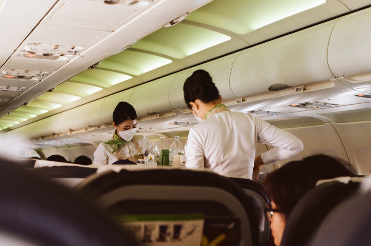 services-04 Flight attendants in white uniforms and masks serving passengers onboard a Vietnam airplane.
